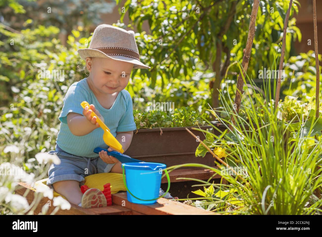 Smiling baby boy is playing with kids garden tools sitting in the ...