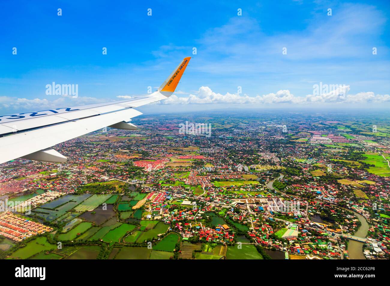 MANILA, PHILIPPINES - FEBRUARY 23, 2013: Cebu Pacific airplane wing above the Manila city suburbs in Philippines Stock Photo