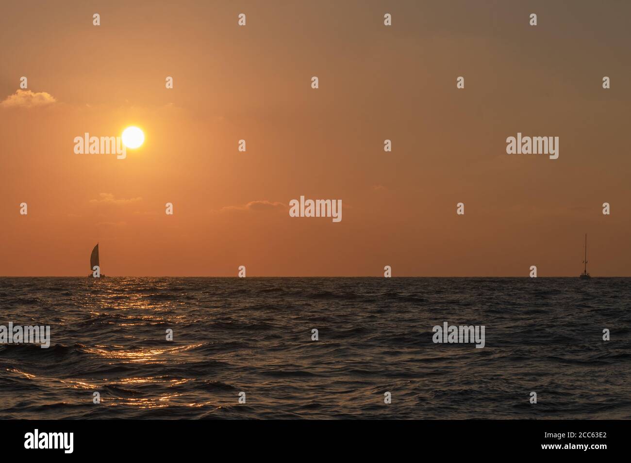 Mediterranean Sun Set, A sail boat crossing the sun at sunset Stock Photo