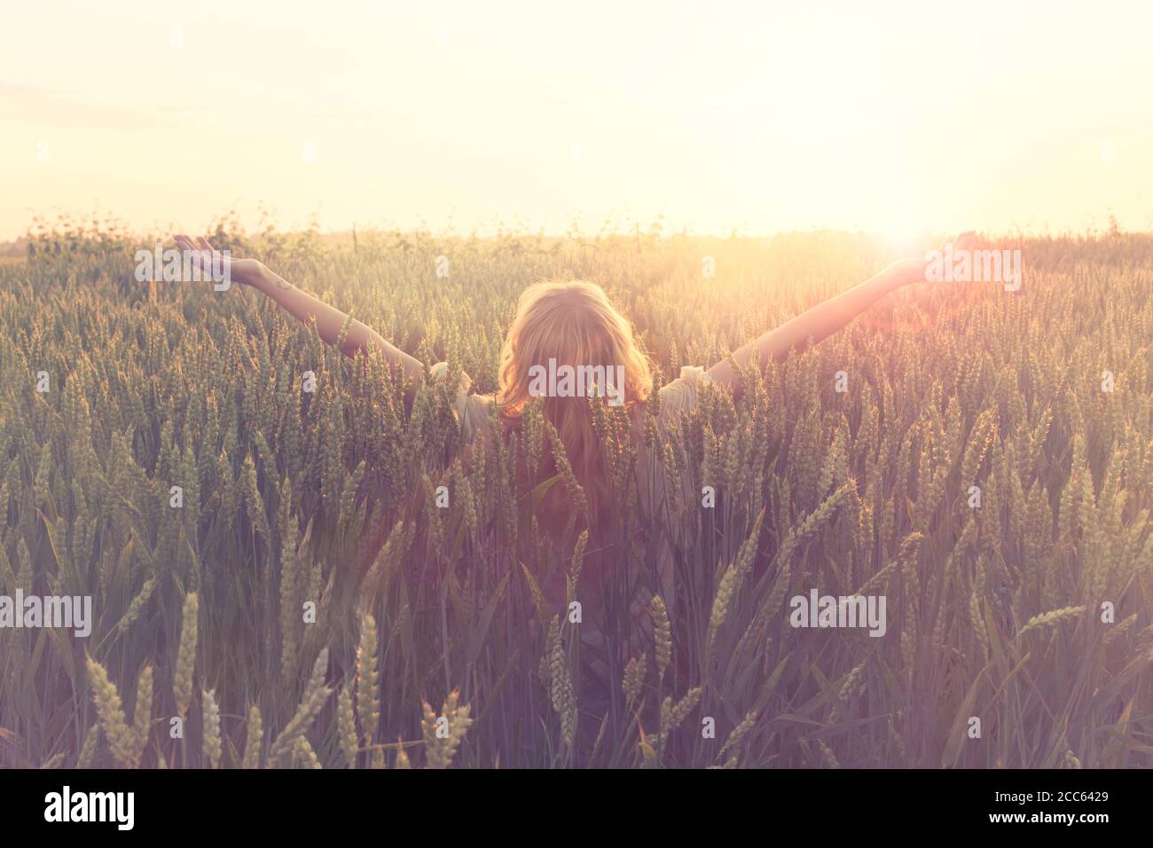 Welcome new day, woman with raised arms embraces the sun Stock Photo