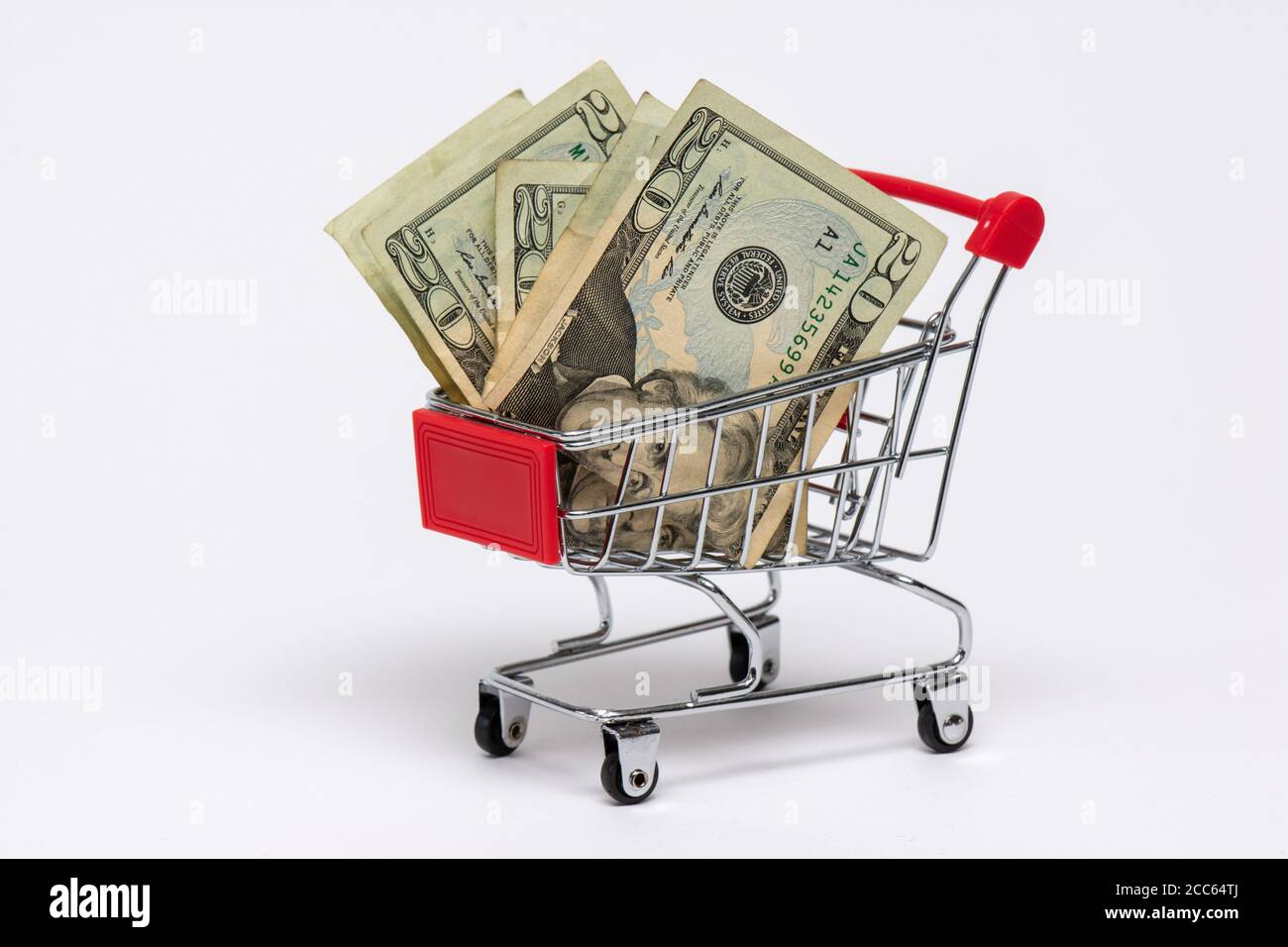 Shopping cart full of twenty dollar bank notes, white background