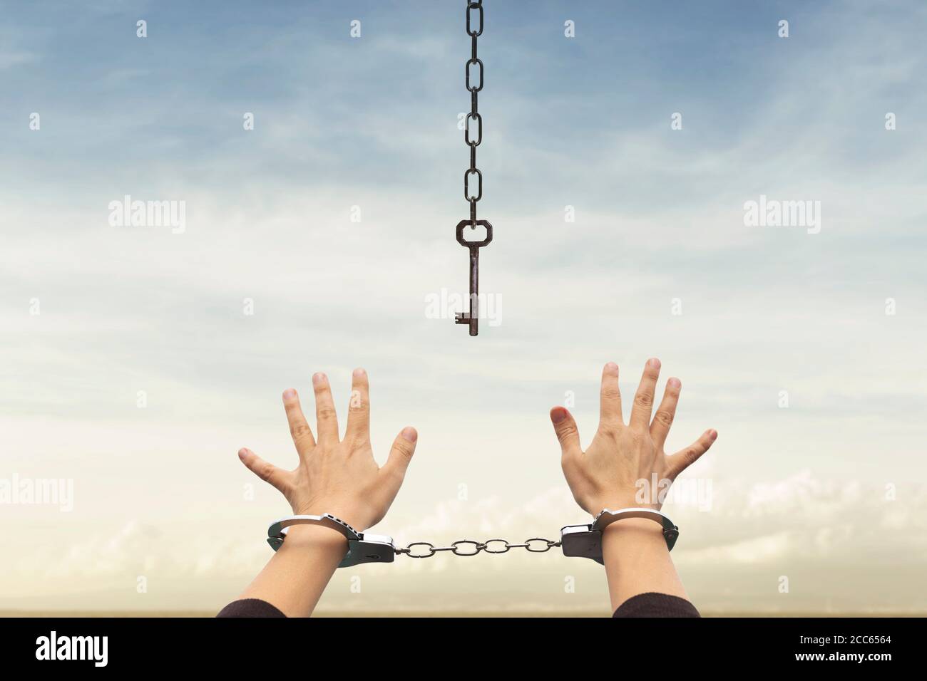person with handcuffed hands tries to take the keys to free themselves but they are too far away Stock Photo