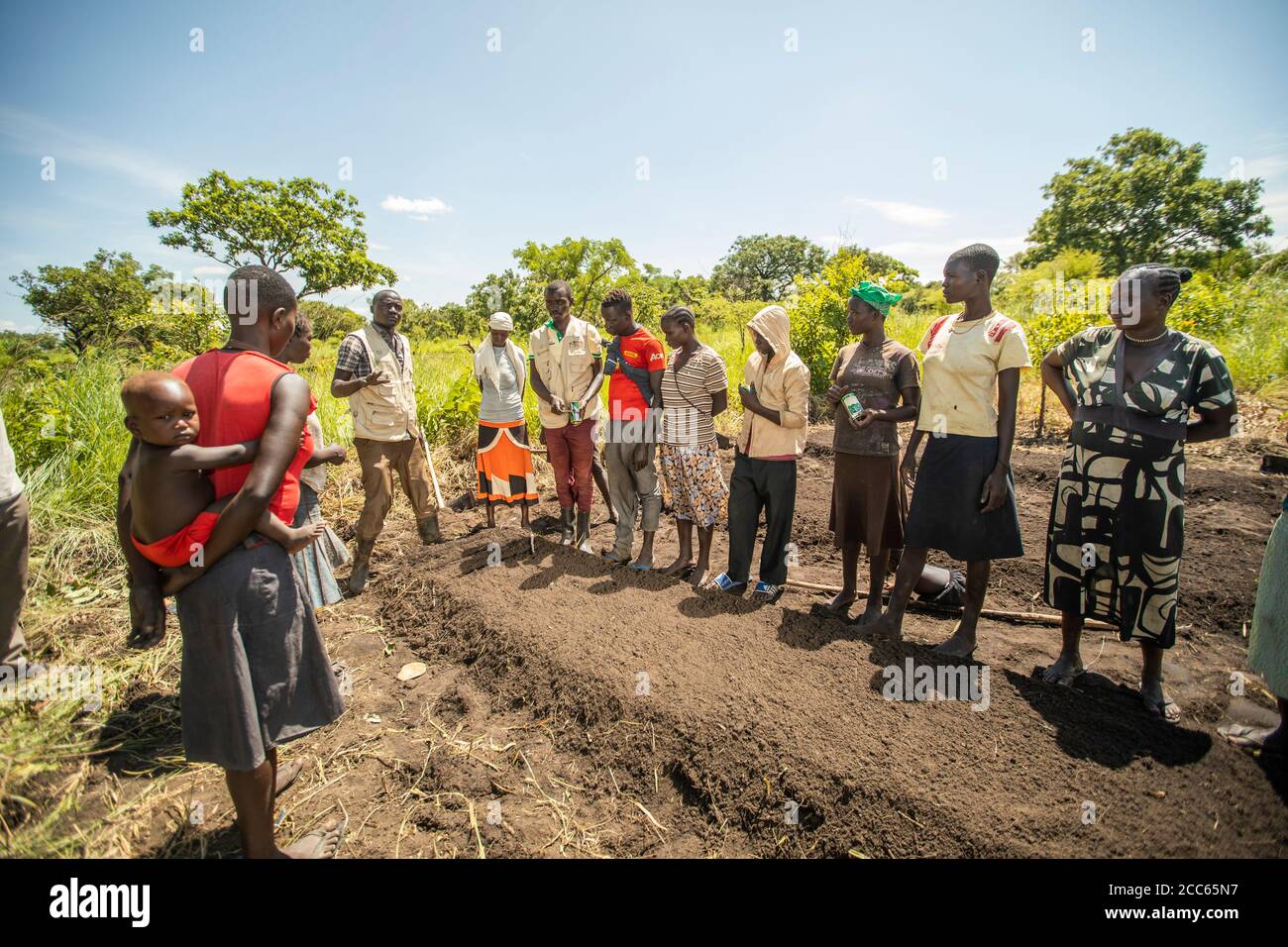 A group of farmers receive agricultural training while standing around a prepared seed bed in Palabek Refugee Settlement in northern Uganda, East Africa. Stock Photo