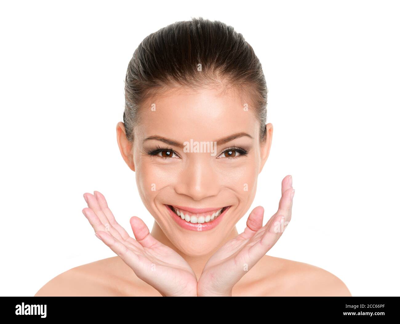 Happy beauty Asian woman showing perfect glowing dewy skin. Facial treatment skincare beautiful mixed race Eurasian model with hands under face Stock Photo