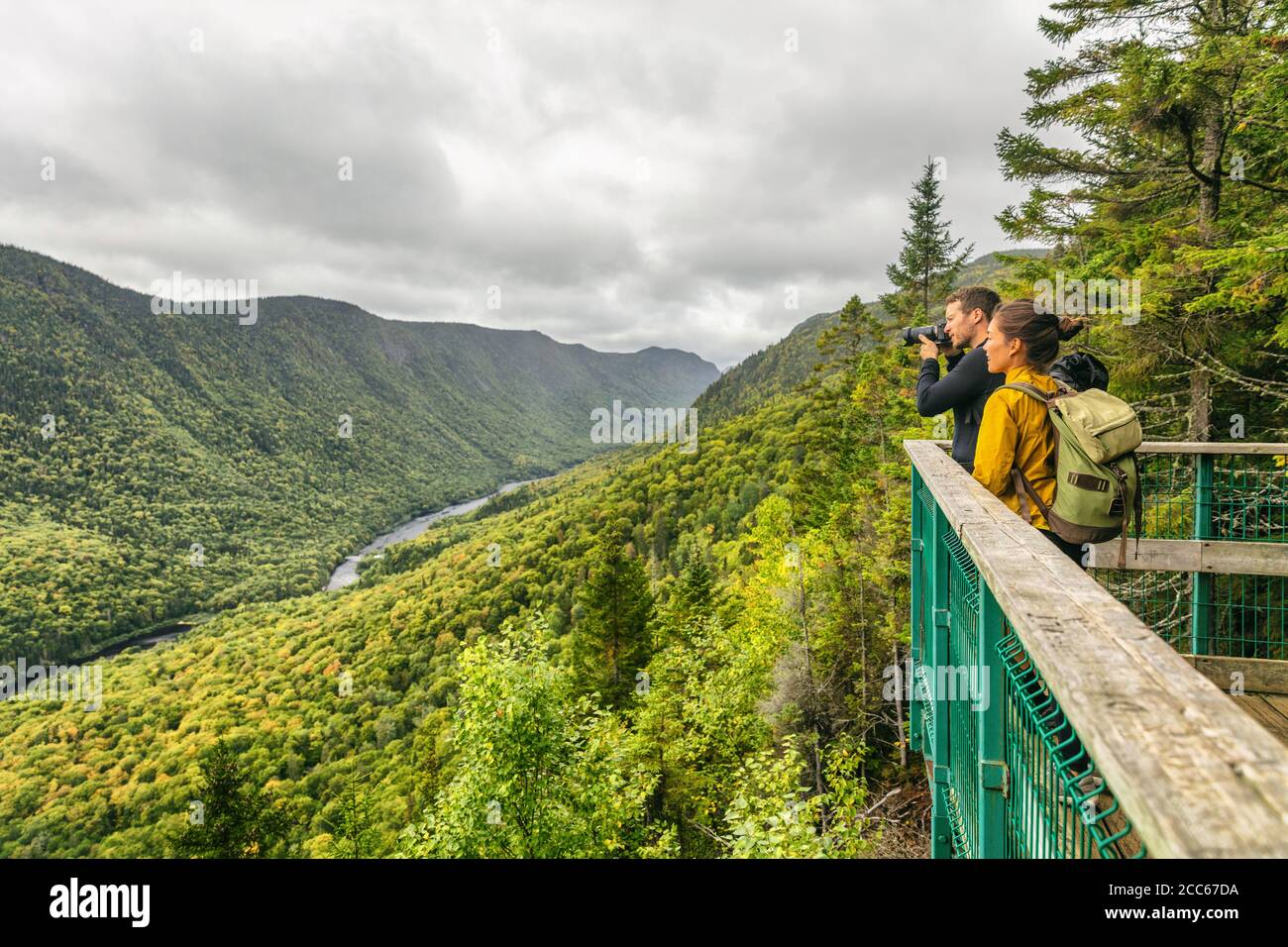 Travel couple hikers hiking in Canada, Quebec Jacques Cartier National Park. Tourists hiking taking photo with camera at view of mountain landscape in Stock Photo