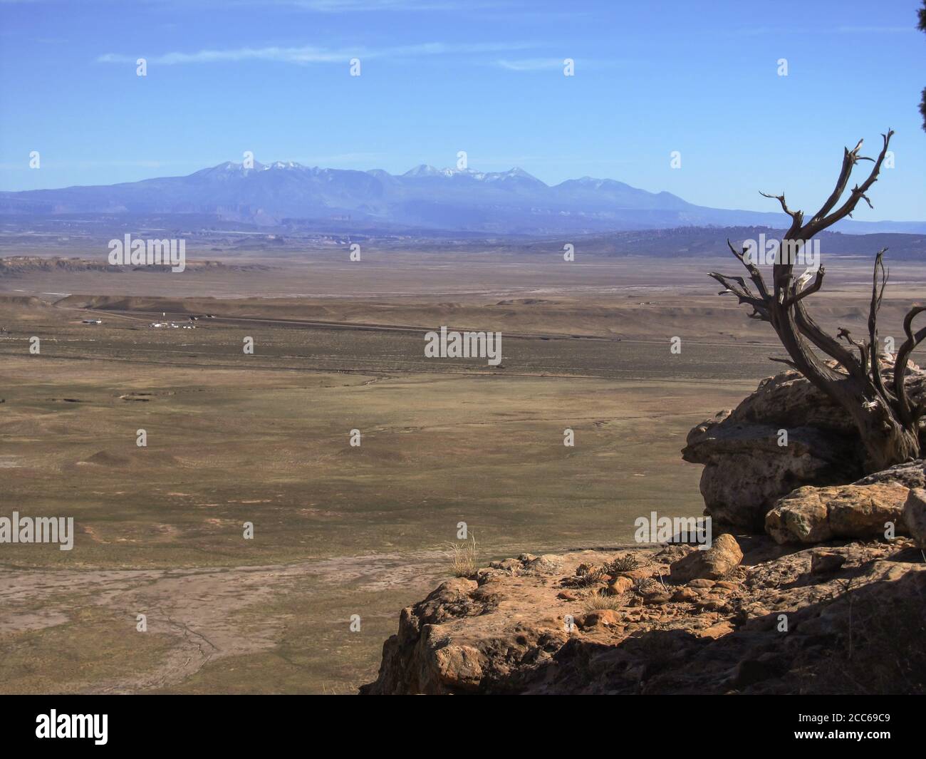 View over the arid eastern Utah Plains with the hazy, snow-capped La Sal Mountains in the Background on a clear sunny day Stock Photo