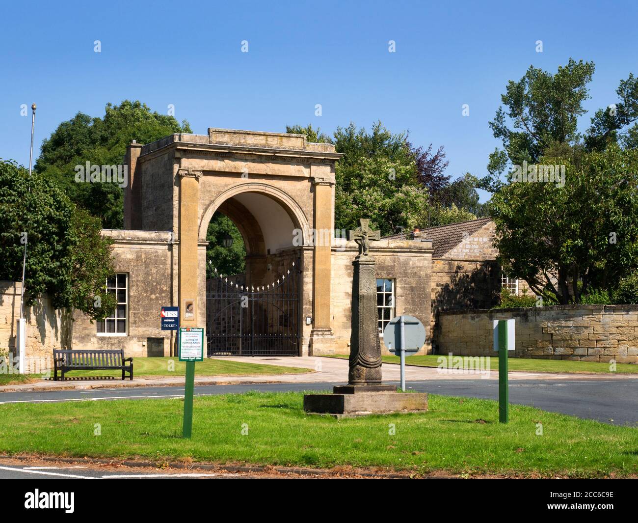 Rudding Gates former entrance to Rudding Park Estate and Saxon Cross on the village green in Follifoot near Harrogate North Yorkshire England Stock Photo