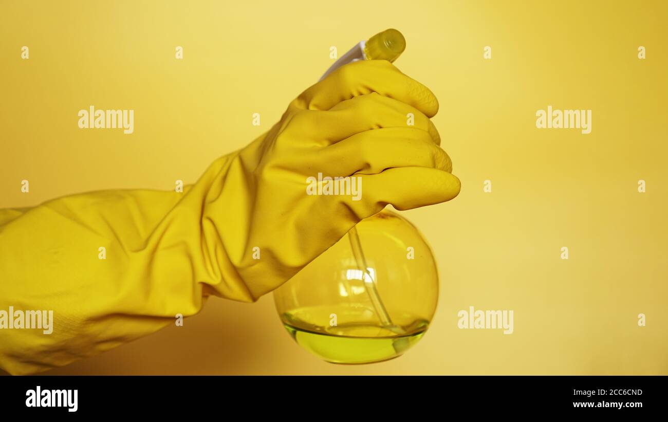 Hand in yellow rubber glove holding plastic spray bottle with cleaning ...