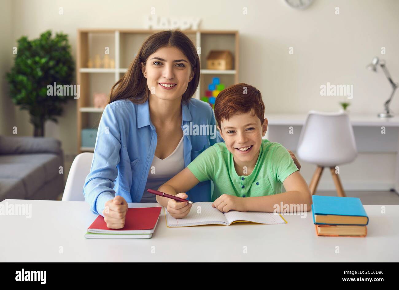 Online education. Happy mother and son looking at camera during webinar with teacher. Child and parent studying at home Stock Photo