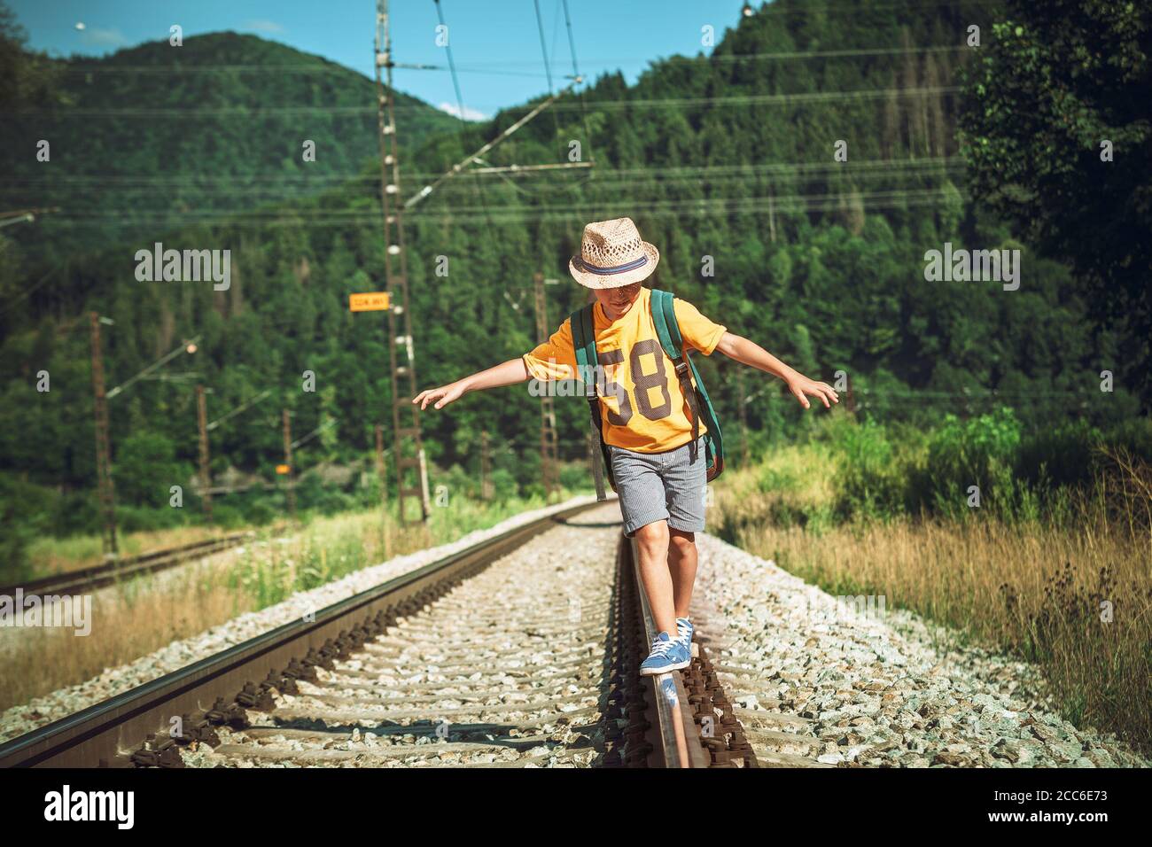 Little boy with backpack walks on railway Stock Photo