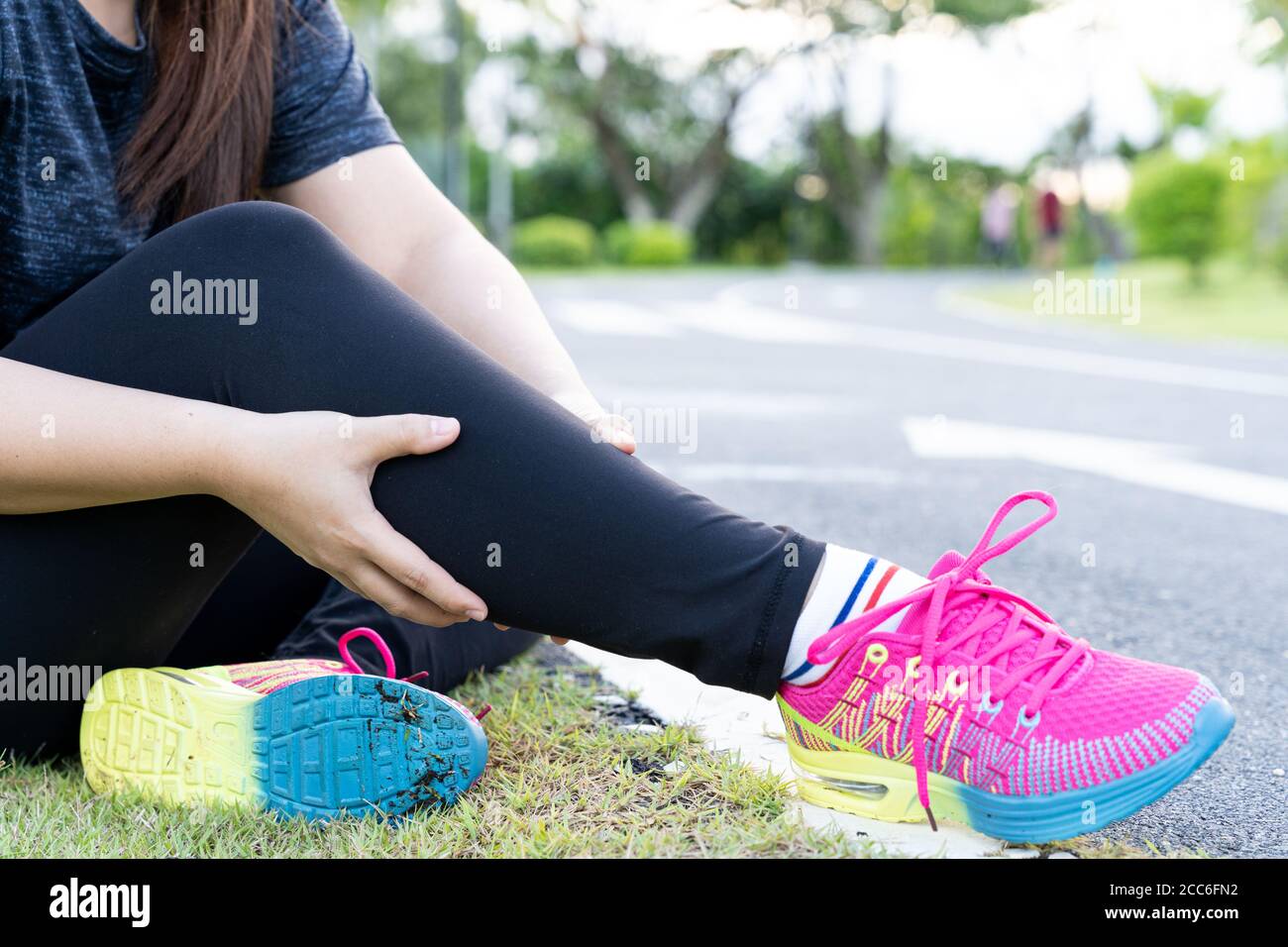 Asian woman massaging her painful calf ache from jogging and running