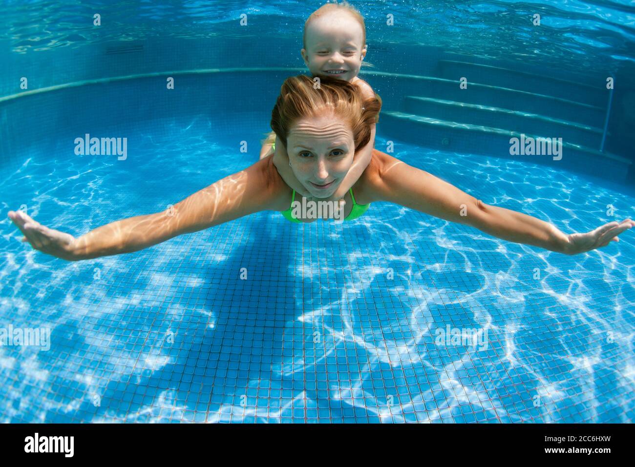 Happy family young mother, baby boy learn to swim, dive underwater