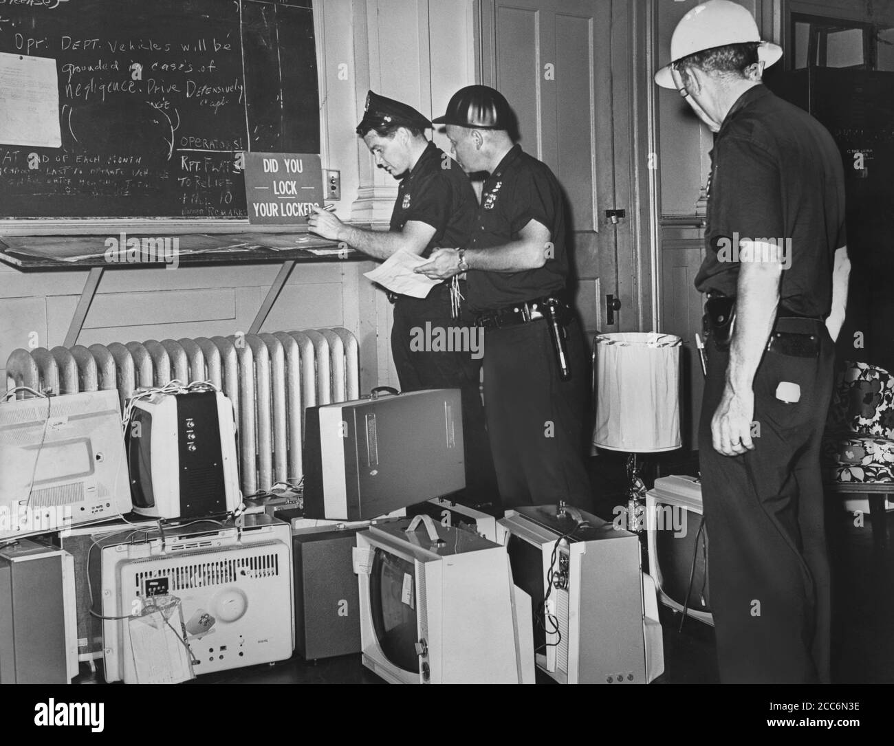 Police Officers Tom McMahon, David Ablett, and Robert Fales documenting confiscated stolen items after night of rioting due to fatal shooting of Teen James Powell by Police Officer Lt. Thomas Gilligan, Brooklyn, New York, USA, John Bottega, World Telegram & Sun, July 22, 1964 Stock Photo