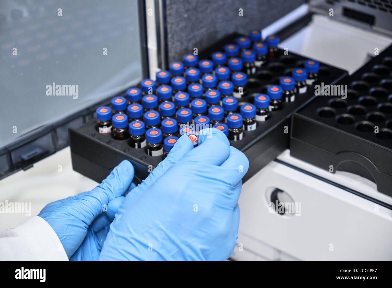 Chemist Putting Vial With A Sample Into Autosampler Of HPLC System chemist-putting-vial-with-a-sample-into-autosampler-of-hplc-system