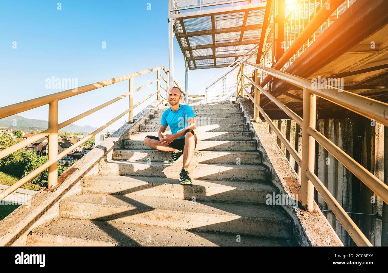 A man sits on stairs after workout set Stock Photo