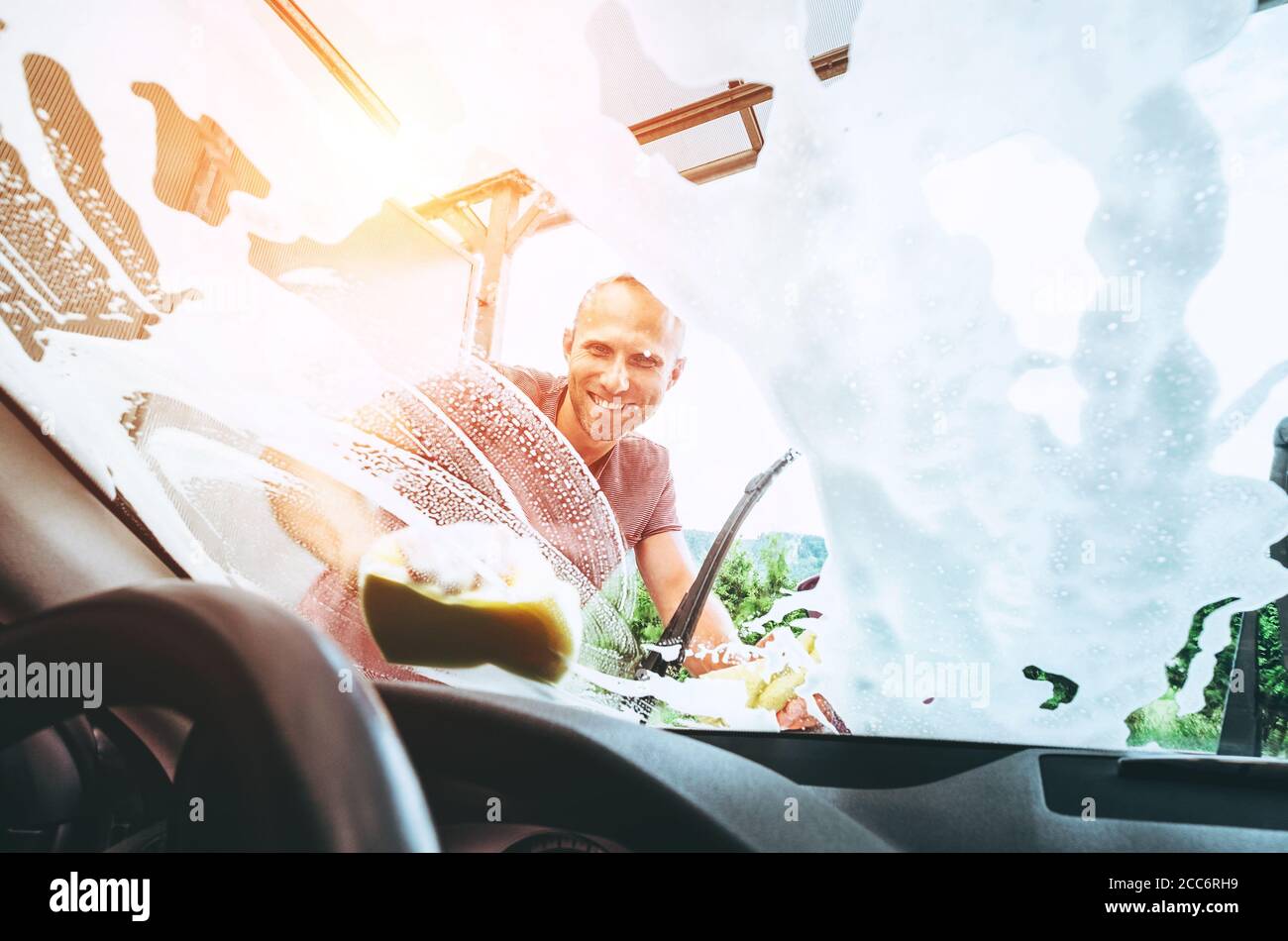 Man washes his car front window Stock Photo