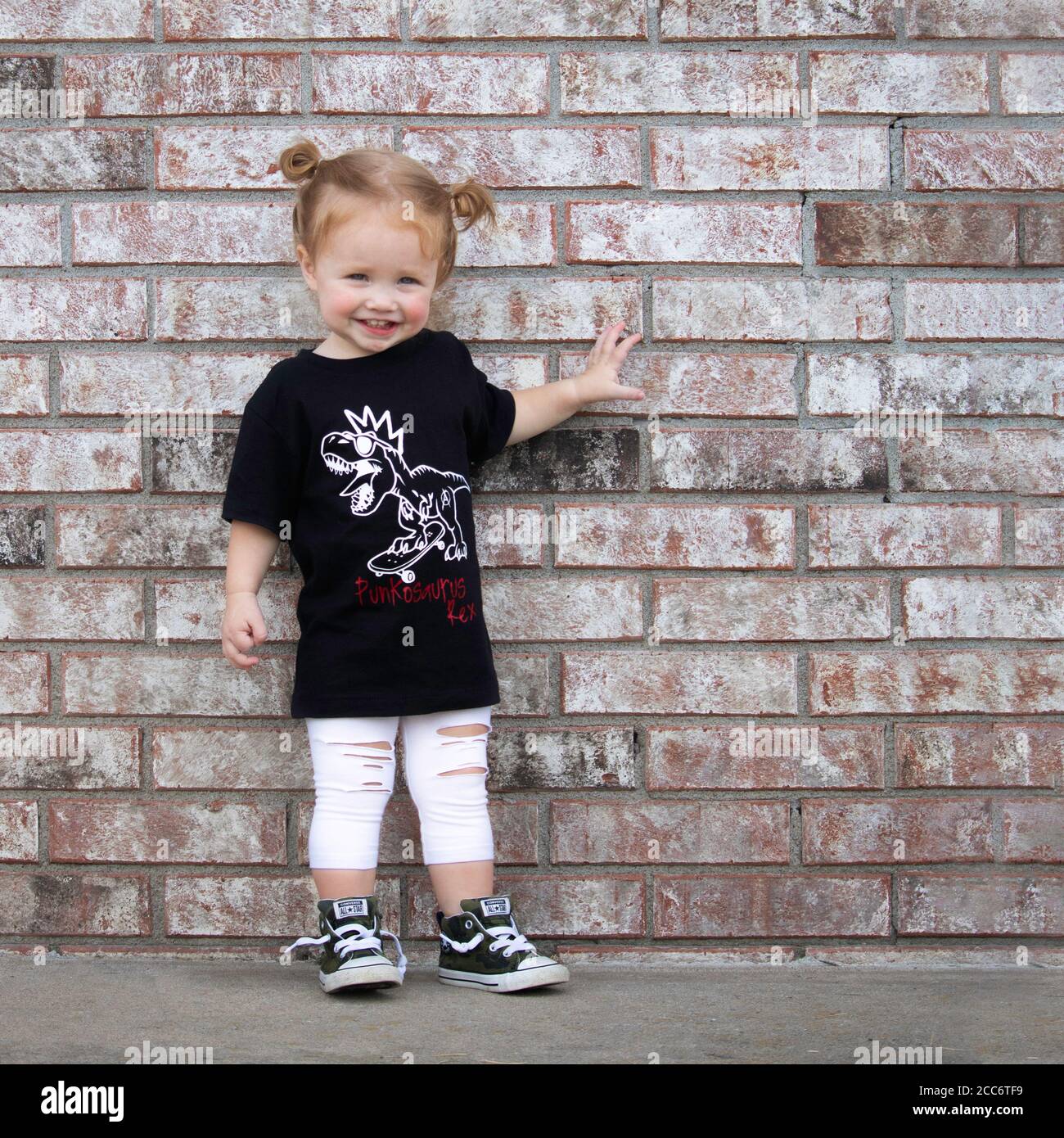Little girl in grunge punk clothes posing on brick wall Stock Photo