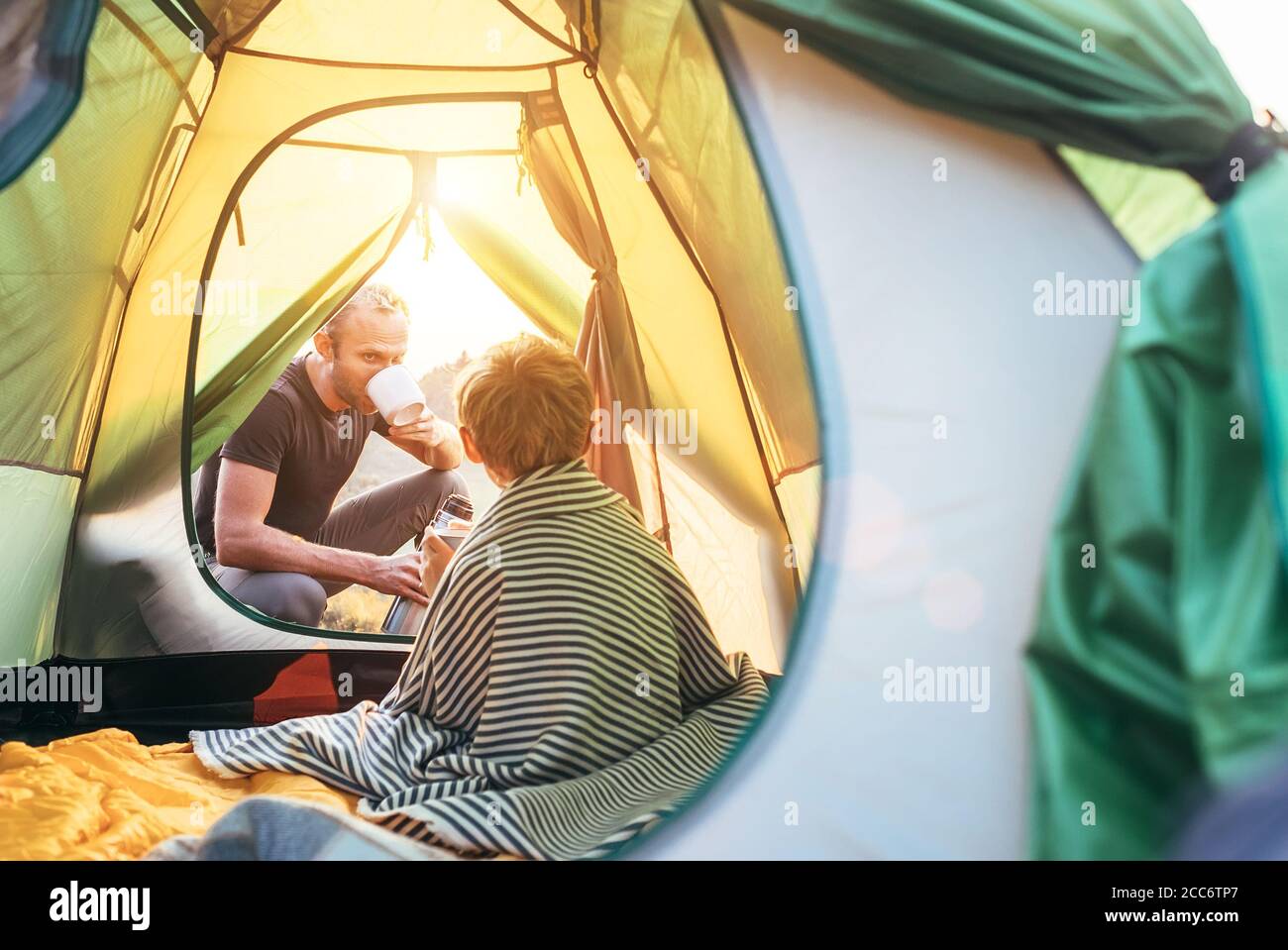 Family lisure concept image. Father and son prepare for camping in mountain, drink tea in ten Stock Photo