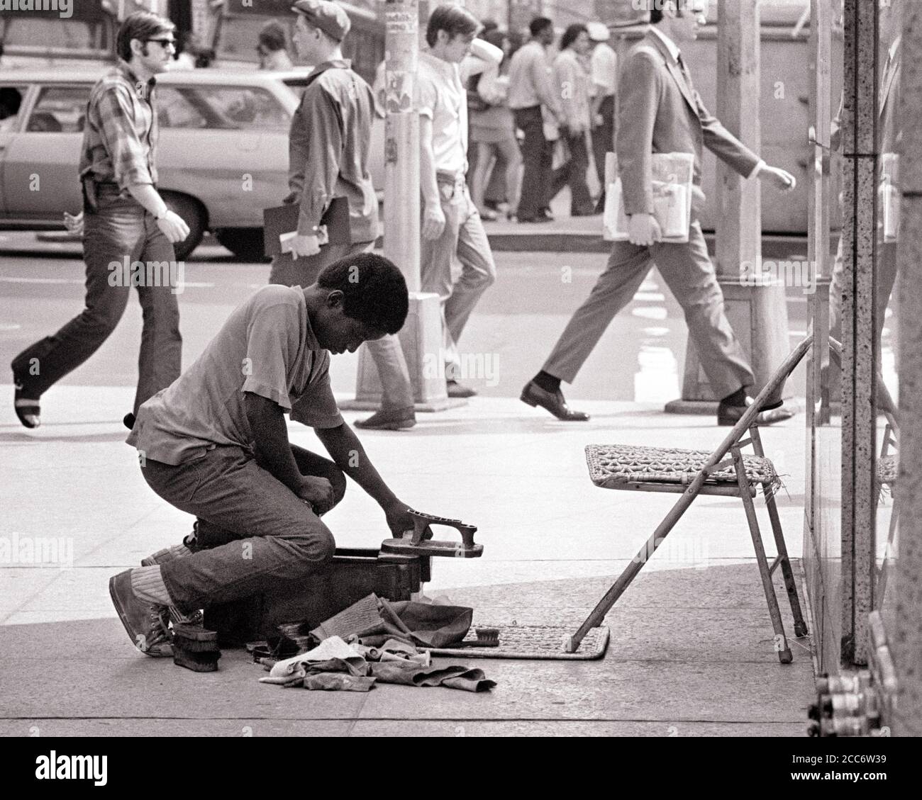 1970s SINGLE ANONYMOUS AFRICAN-AMERICAN TEENAGE BOY ENTREPRENEUR WITH SHOE SHINE BUSINESS SET UP ON CITY STREET CORNER NYC USA - b24291 HAR001 HARS FULL-LENGTH PERSONS TRADITIONAL UNITED STATES OF AMERICA CORNER TEENAGE BOY KIT CONFIDENCE B&W NORTH AMERICA GOALS NORTH AMERICAN DREAMS POLISH STRENGTH CUSTOMER SERVICE AFRICAN-AMERICANS COURAGE AFRICAN-AMERICAN EXTERIOR PROGRESS BLACK ETHNICITY INDEPENDENT PRIDE ON OPPORTUNITY UP NYC OCCUPATIONS CONCEPTUAL NEW YORK CITIES ENTREPRENEUR TEENAGED NEW YORK CITY ANONYMOUS GROWTH SHINE BLACK AND WHITE HAR001 OLD FASHIONED AFRICAN AMERICANS Stock Photo