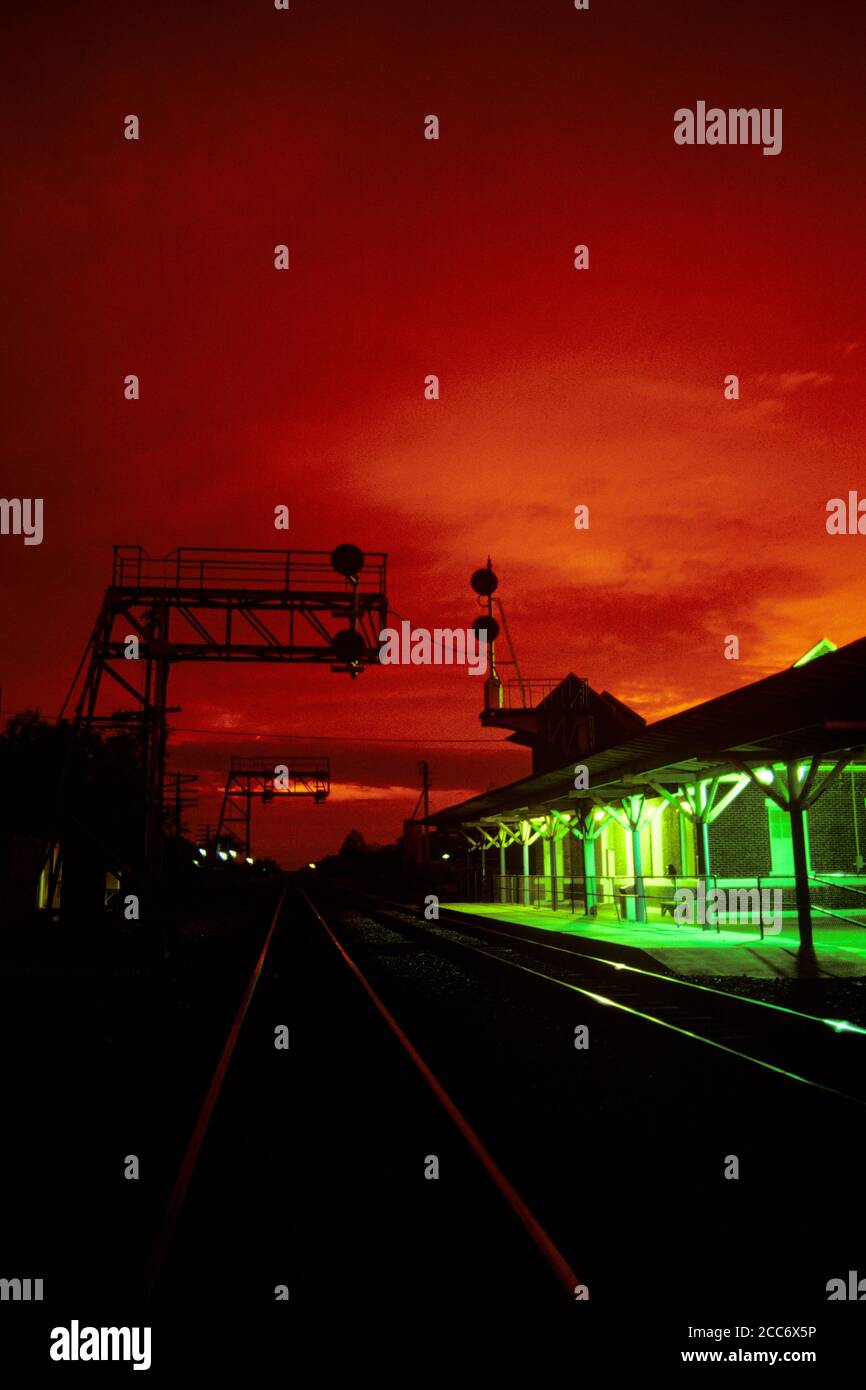 1990s RED SKY ABOVE GREEN RAILROAD STATION TRACKS CONVERGING IN DISTANCE SEABOARD SYSTEM SELMA NORTH CAROLINA  - kr100455 SMT001 HARS NORTH CAROLINA DEPOT OLD FASHIONED SEABOARD Stock Photo