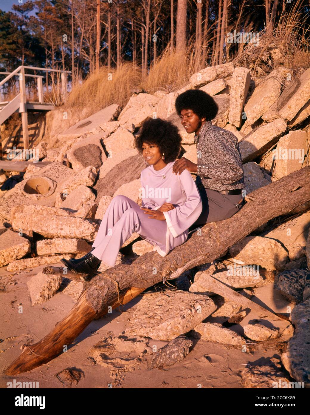 1970s ROMANTIC AFRICAN-AMERICAN COUPLE WATCHING SUNSET ON ROCKY BEACH FASHION CLOTHES AND HAIRSTYLES  - ks9161 CRS001 HARS FEMALES MARRIED RURAL SPOUSE HUSBANDS HEALTHINESS HOME LIFE COPY SPACE FRIENDSHIP HALF-LENGTH LADIES PERSONS INSPIRATION AFRO CARING MALES CONFIDENCE PARTNER DATING SHORE DREAMS ROCKY HAPPINESS DISCOVERY LEISURE AFRICAN-AMERICANS AFRICAN-AMERICAN AND HAIRSTYLE BLACK ETHNICITY ATTRACTION BEACHES CONNECTION COURTSHIP FRO HAIRSTYLES SANDY STYLISH PERSONAL ATTACHMENT POSSIBILITY AFFECTION EMOTION RELAXATION SOCIAL ACTIVITY TOGETHERNESS WIVES YOUNG ADULT MAN YOUNG ADULT WOMAN Stock Photo