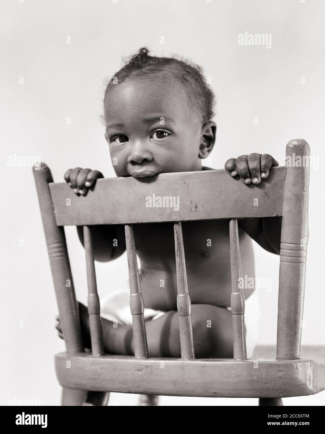 https://c8.alamy.com/comp/2CC6XTM/1940s-teething-african-american-baby-boy-looking-at-camera-sitting-chewing-on-back-of-painted-chair-n249-har001-hars-parenting-chewing-healthiness-illness-home-life-copy-space-full-length-danger-males-risk-bw-sadness-eye-contact-healthcare-temptation-wellness-prevention-protection-strength-healing-african-americans-african-american-diagnosis-black-ethnicity-pride-health-care-of-on-impairment-painted-treatment-baby-teeth-conceptual-lead-baby-boy-caution-deciduous-teeth-growth-juveniles-milk-teeth-black-and-white-disease-har001-old-fashioned-teething-african-americans-2CC6XTM.jpg