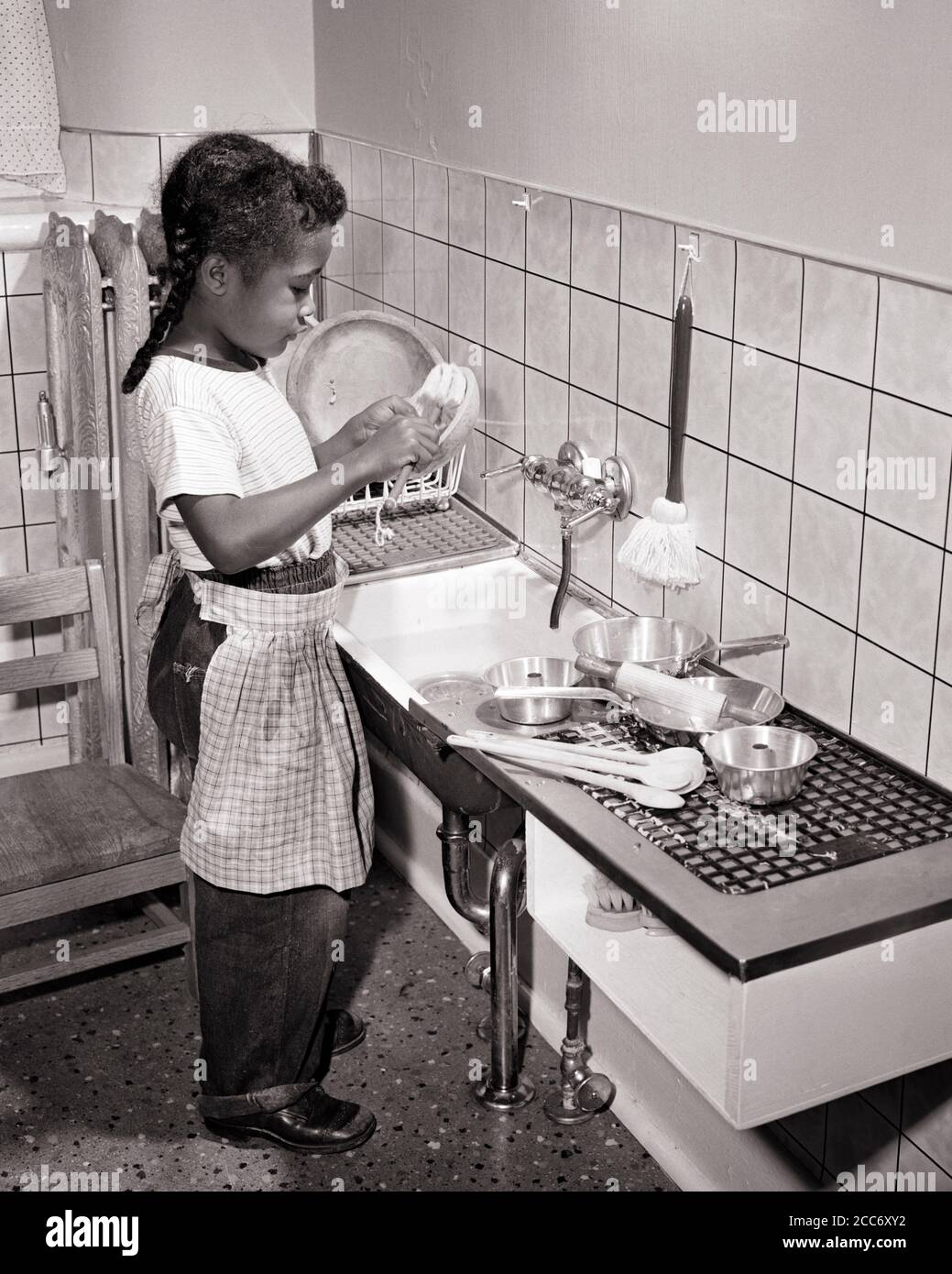 1950s 1960s LITTLE AFRICAN-AMERICAN GIRL WASHING HER TOY DISHES POT PANS IN CHILD SIZED KITCHEN SINK AT NURSERY SCHOOL DAY CARE - n561 HAR001 HARS HEALTHINESS COPY SPACE FULL-LENGTH SINK CONFIDENCE B&W PANS GOALS CHORE AFRICAN-AMERICANS AFRICAN-AMERICAN KNOWLEDGE BLACK ETHNICITY PRIDE OPPORTUNITY CONNECTION ANONYMOUS COOPERATION GROWTH JUVENILES TASK BLACK AND WHITE HAR001 OLD FASHIONED AFRICAN AMERICANS Stock Photo
