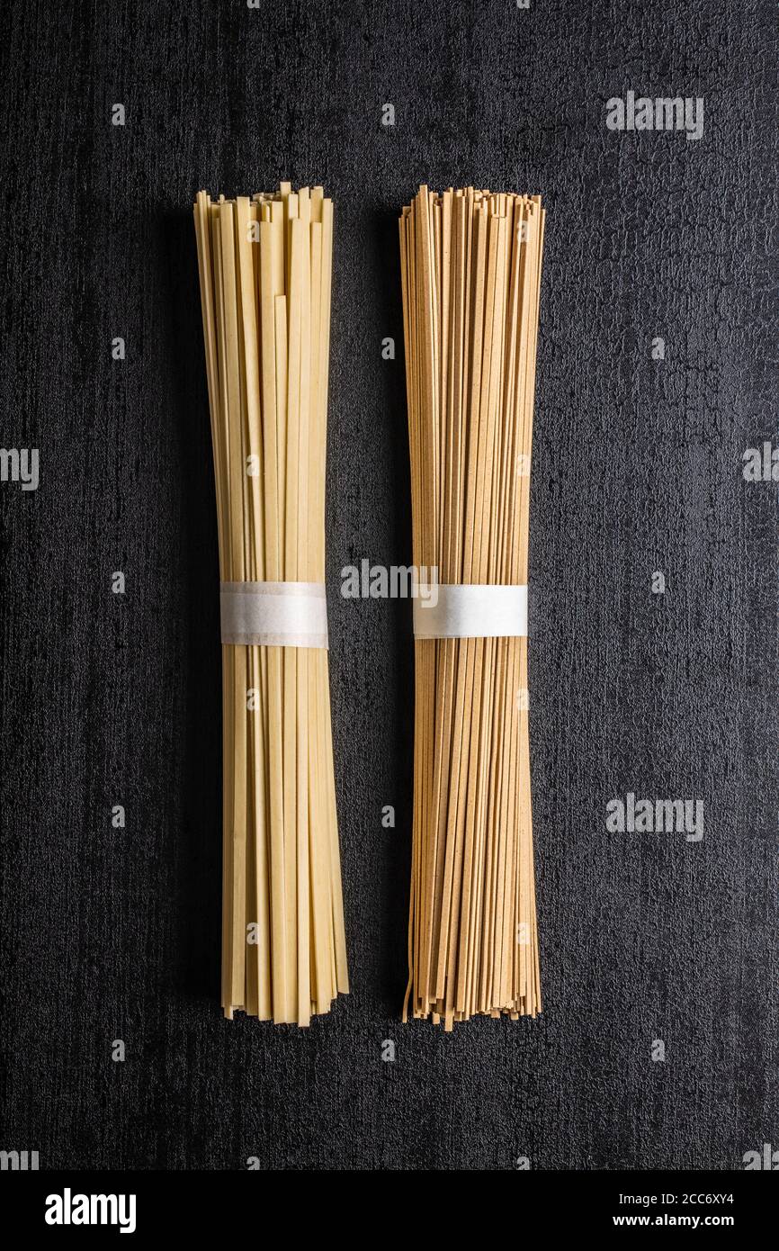 Uncooked soba and udon noodles. Traditional Japanese noodles on black table. Top view Stock