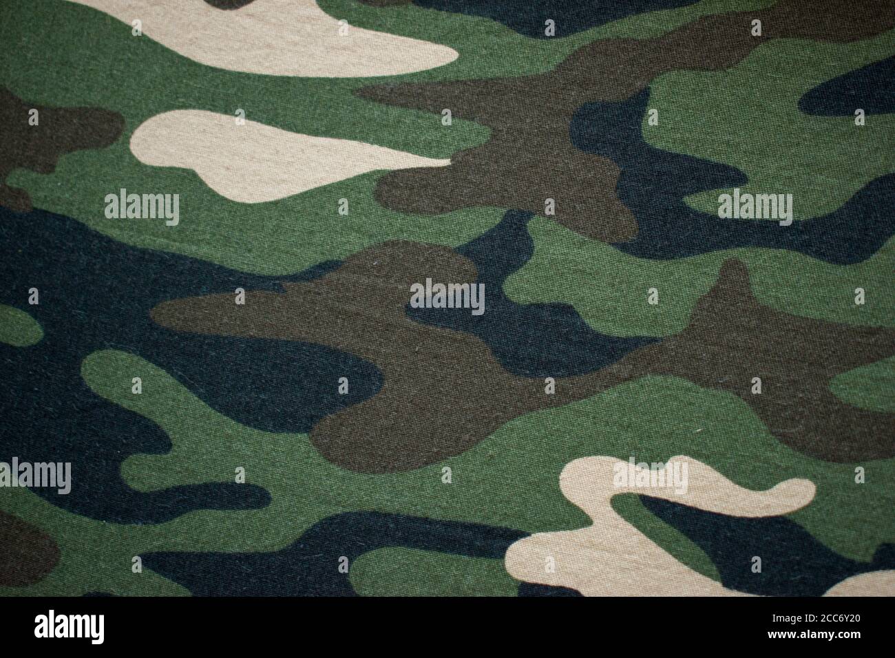 Green background with beige, black and brown spots. Camouflage fabric for sewing military uniform. Stock Photo