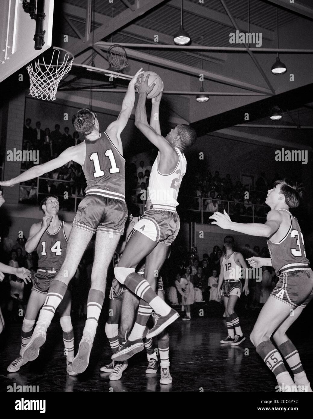 1960s SINGLE ANONYMOUS AFRICAN-AMERICAN YOUNG MAN ATHLETE JUMPING TO SCORE BASKETBALL GOAL SURROUNDED BY CAUCASIAN COMPETITORS - s17545 HAR001 HARS OLD TIME NOSTALGIA OLD FASHION 1 FITNESS JUVENILE STYLE HOOP HEALTHY YOUNG ADULT NET TEAMWORK COMPETITION SCORE ATHLETE GOAL LIFESTYLE ATHLETICS PHYSICAL FITNESS PERSONS INSPIRATION MALES TEENAGE BOY ATHLETIC CONFIDENCE PLAYERS B&W GOALS ACTIVITY PHYSICAL STRENGTH UNIVERSITIES AFRICAN-AMERICANS AFRICAN-AMERICAN AND EXCITEMENT HOOPS PROGRESS RECREATION SURROUNDED BLACK ETHNICITY PRIDE BY TO HIGHER EDUCATION ATHLETES FLEXIBILITY MUSCLES SCORING Stock Photo