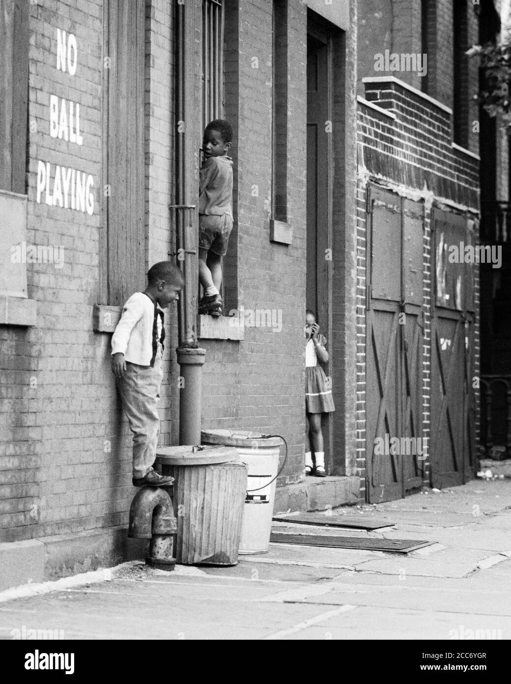 1970s THREE ANONYMOUS YOUNG AFRICAN-AMERICAN CHILDREN PLAYING HIDE AND SEEK ON CITY STREET WITH NO BALL PLAYING WRITTEN ON WALL - w5854 HAR001 HARS URBAN DEPRESSION SIDEWALK DOORWAY EXPRESSION OLD TIME BUSY SURPRISE NOSTALGIA BROTHER TAG OLD FASHION SISTER POVERTY 1 JUVENILE FACIAL SAFETY COMPETITION WORRY LIFESTYLE BRICK FEMALES BROTHERS MOODY POOR HEALTHINESS HOME LIFE COPY SPACE FRIENDSHIP FULL-LENGTH CANS MALES RISK SIBLINGS SISTERS EXPRESSIONS TROUBLED B&W CONCERNED SADNESS MEAN WELLNESS TRASH ADVENTURE DISCOVERY HIDE STREETS WELFARE AFRICAN-AMERICANS AFRICAN-AMERICAN AND CHOICE Stock Photo