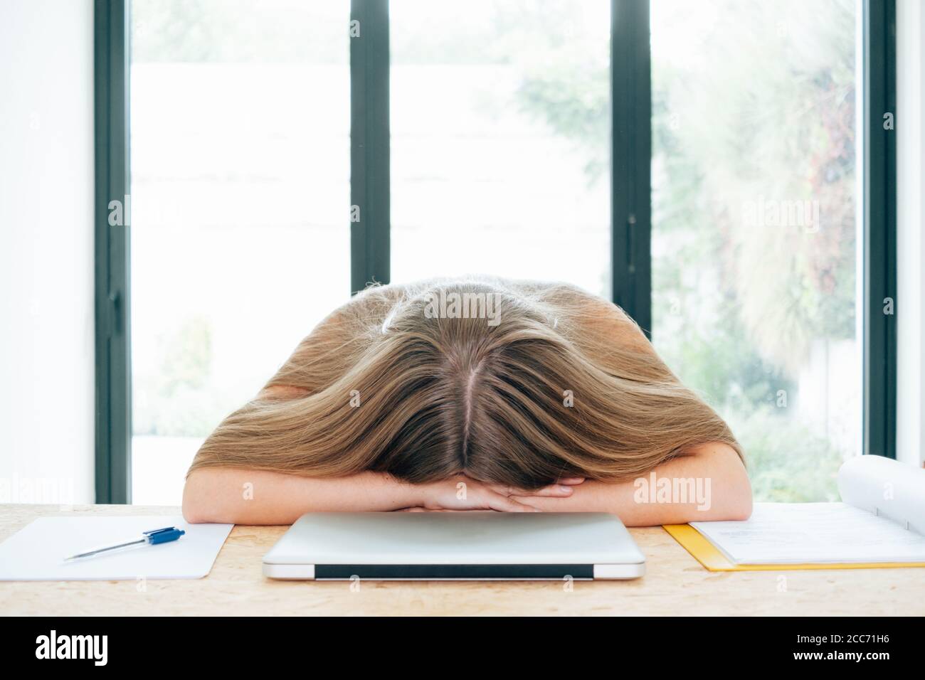 young frustrated woman laid head down on table work, fatigued worker or