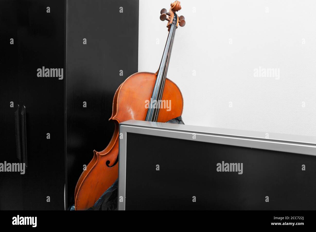 A cello hidden behind a tv set, indoor shot Stock Photo