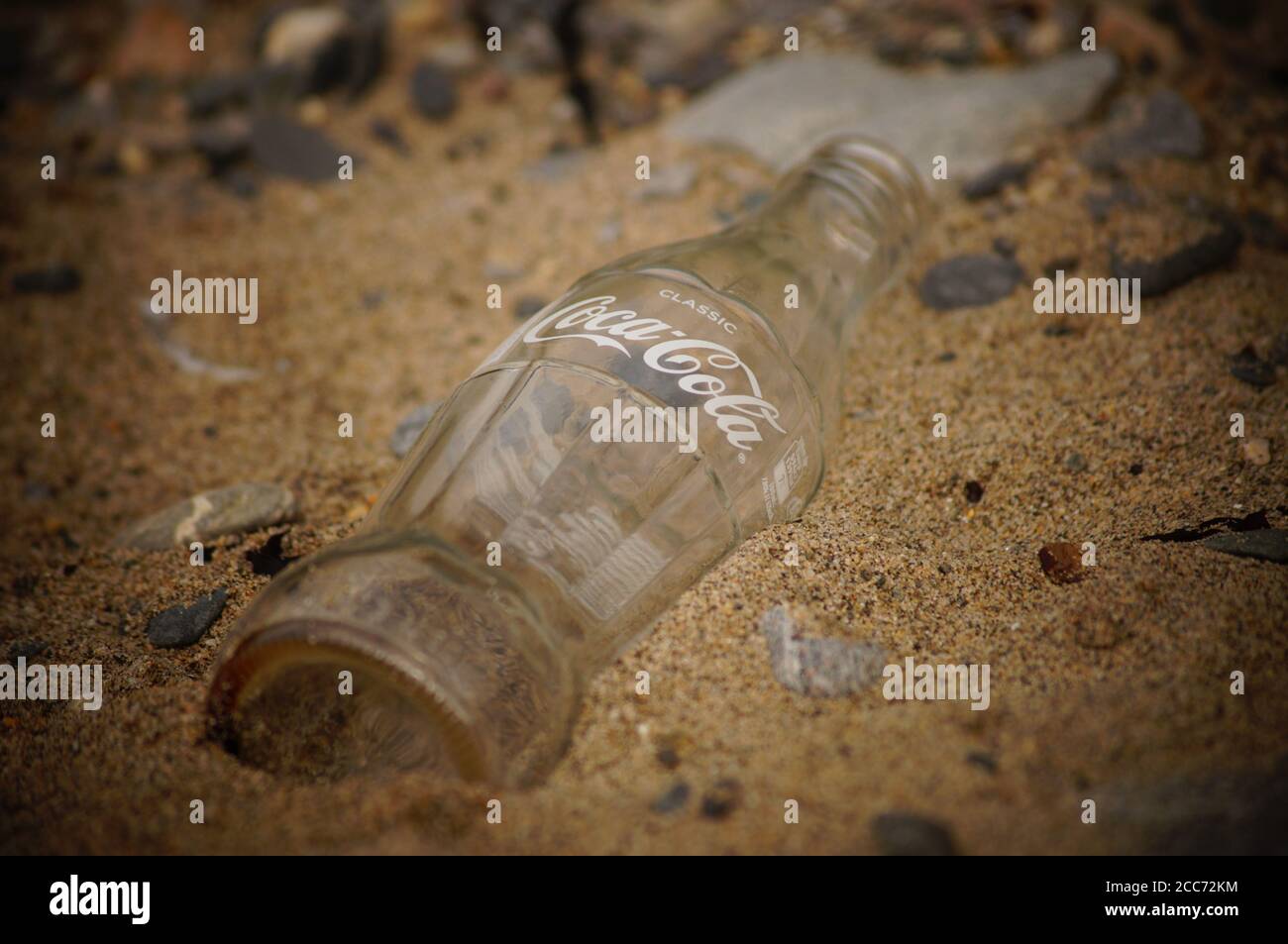 Coca Cola bottle in sand (glass bottle) Stock Photo