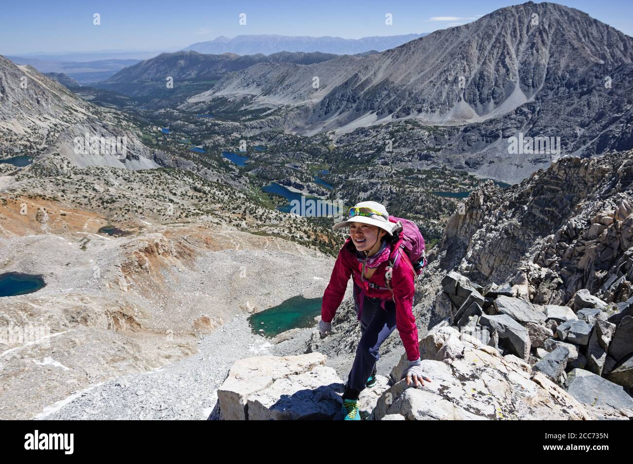Asian woman reaching the top of Treasure Peak after climbing up the East Ridge Stock Photo