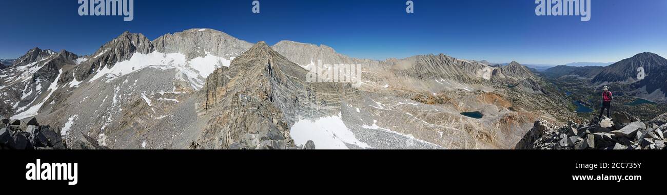 panorama of a woman on the East Summit of Treasure Peak in Little Lakes Valley of the Eastern Sierra Nevada Mountains with Bear Creek Spire Mount Dade Stock Photo