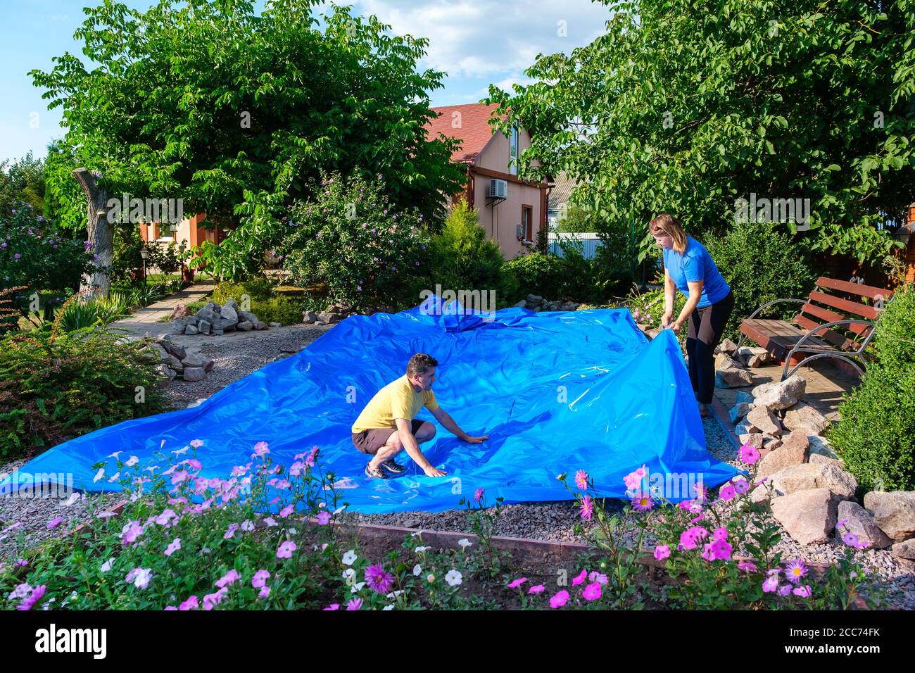 family lays a blue HDPE plastic sheet on the ground to set up a fish