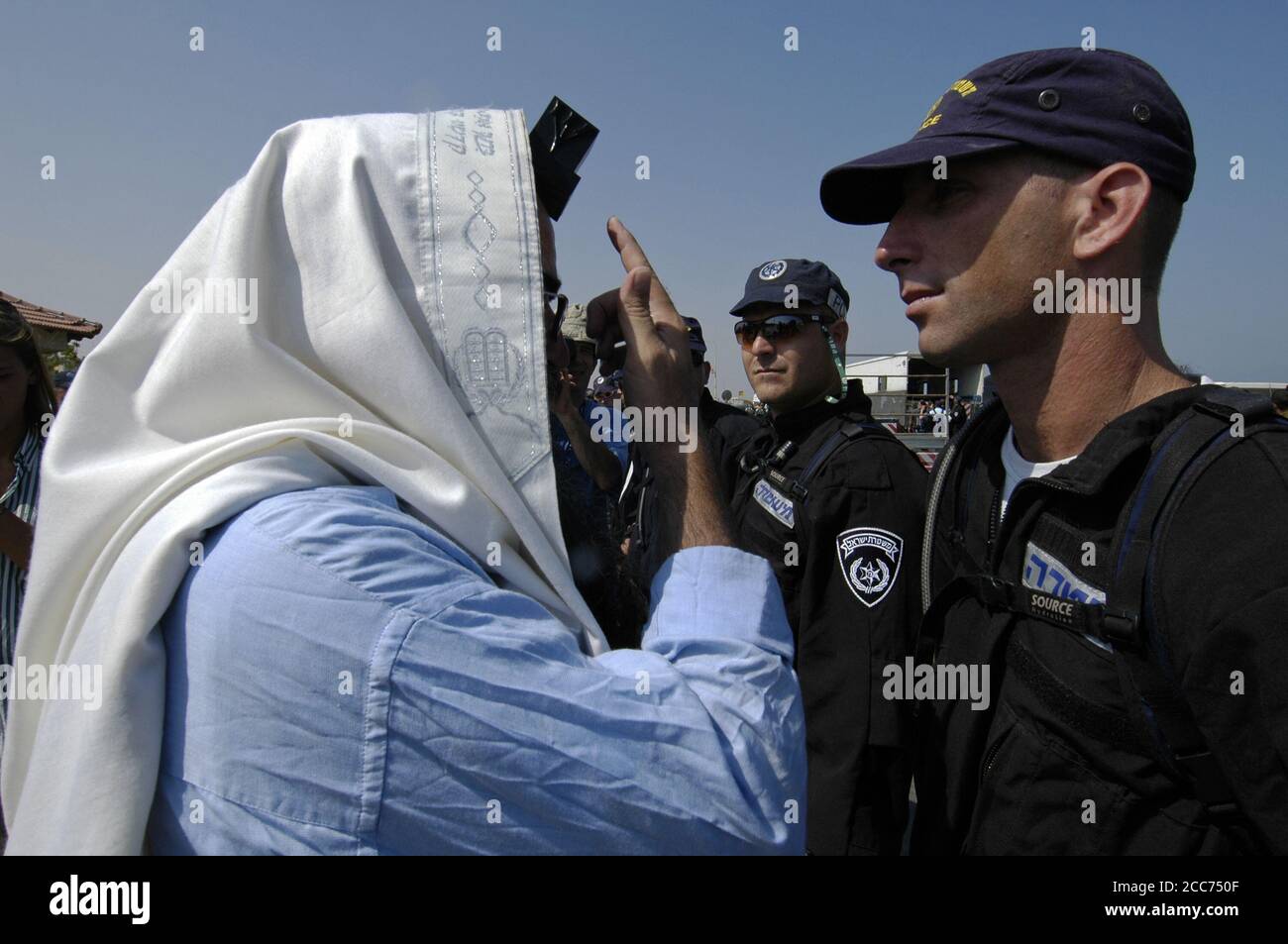 A religious Jewish settler wrapped with a Talit shawl and Tfilin confronts Israeli police during Jewish settlements evacuation from Gaza strip Stock Photo