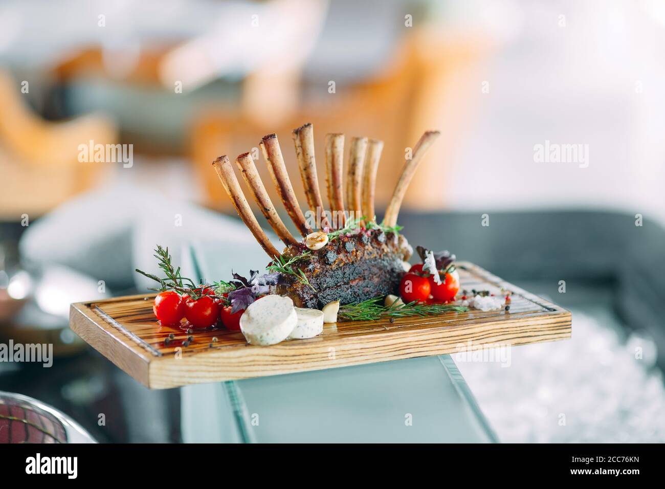 Dish Rack of Lamb with tomatoes on a wooden tray. Stock Photo