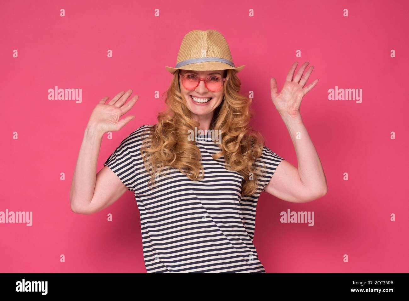 woman wear sunglasses and hat smiling and waving palm saying hello. Stock Photo