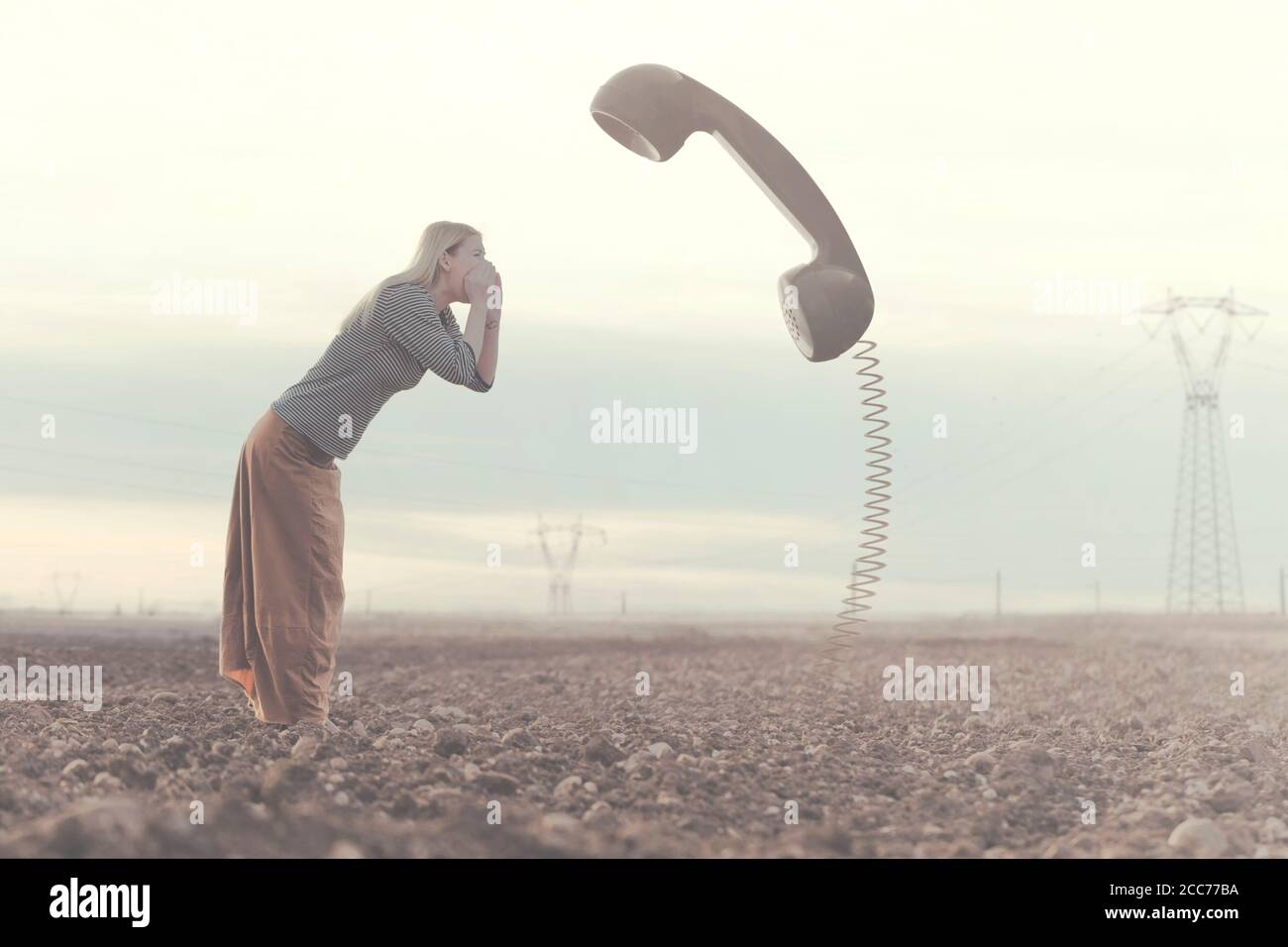 surreal moment between a woman screaming in a huge phone connected to the ground Stock Photo