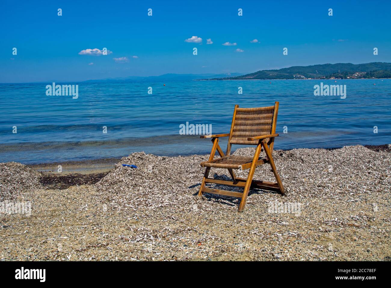 Good old wooden summer chair on the beach in Greece. The chair is a symbol of enjoyment and relaxation by the sea. Stock Photo
