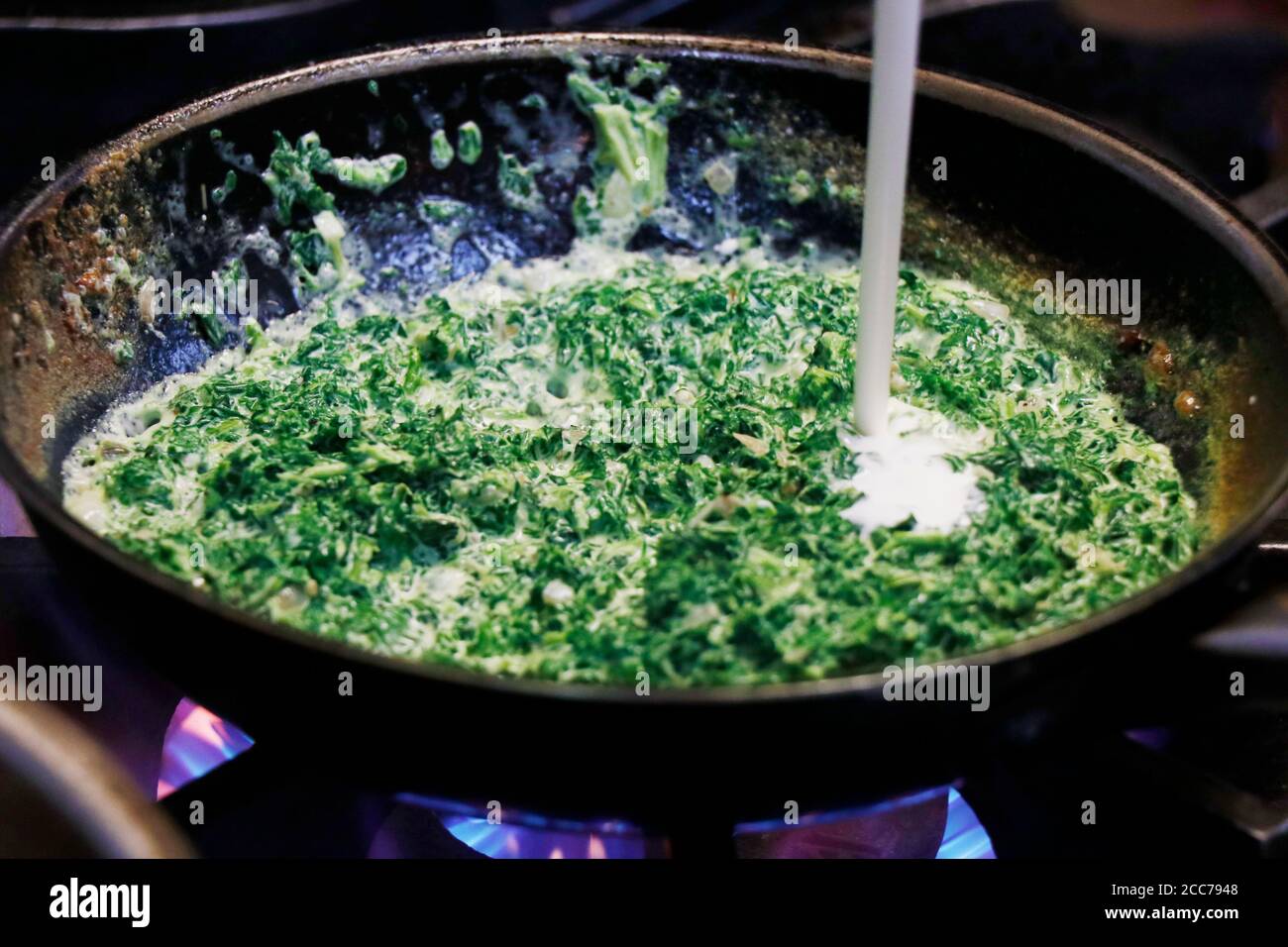creamy baby spinach in a cooking pan on fire Stock Photo