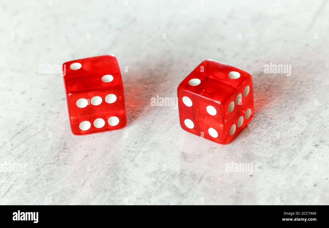 Two translucent red craps dices on white board showing Hard Four