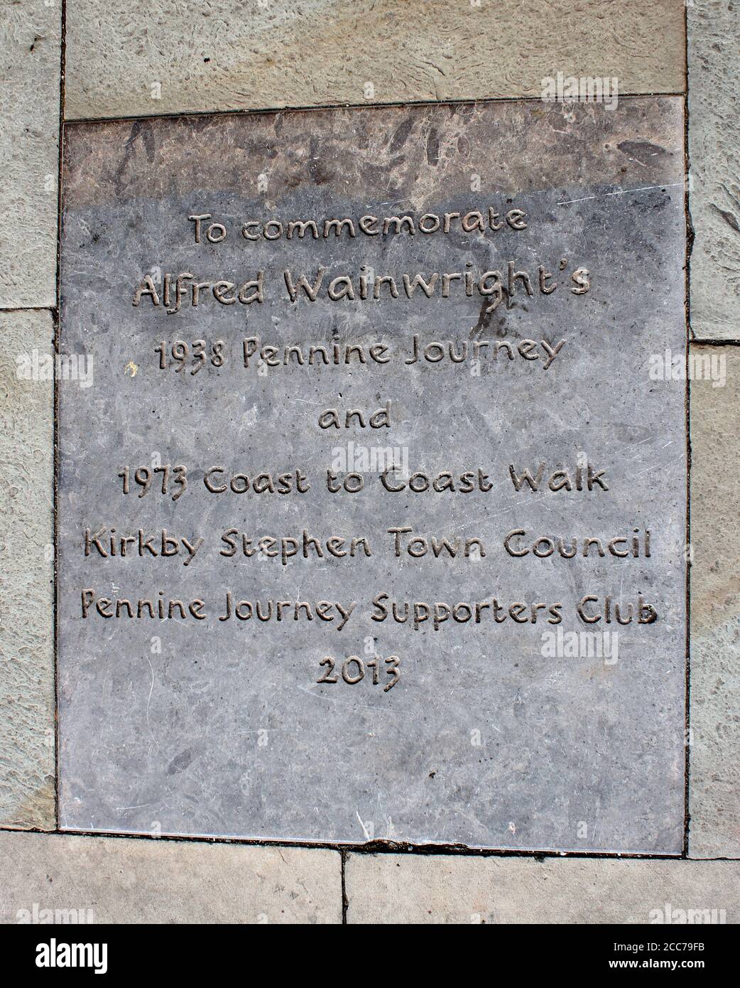 Commemorative engraving paving stone in pavement footpath outside the cloisters, Kirkby Stephen, Cumbria commemorating Alfred Wainwright's walks. Stock Photo