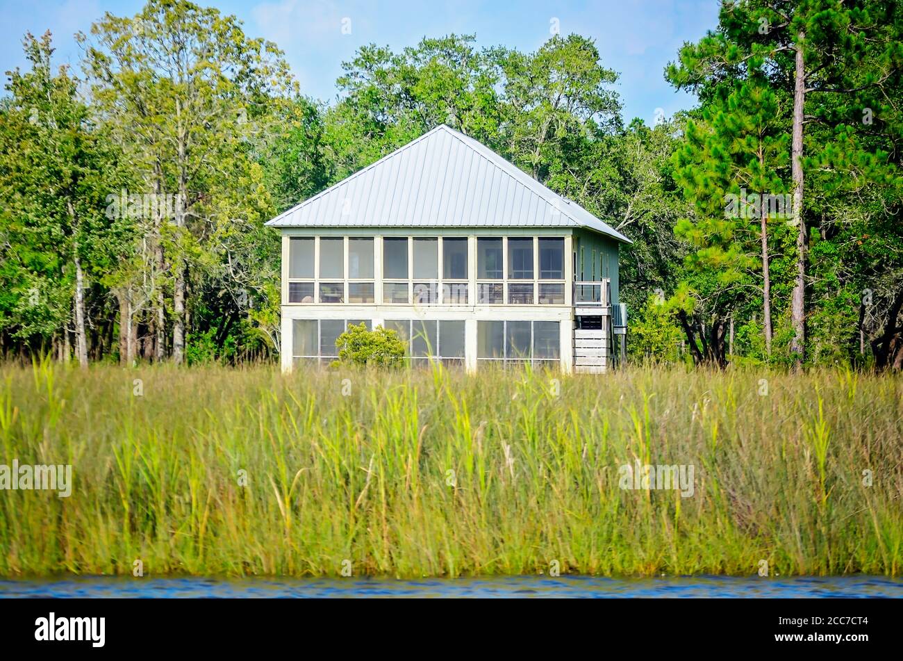 A twostory family home is surrounded by marsh grass on Fowl River