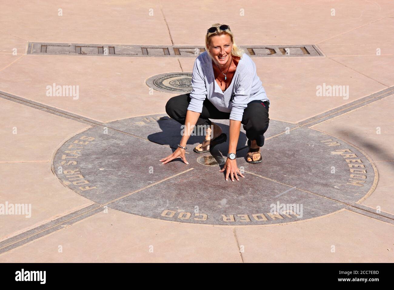 One woman touching the ground of four states at one time, Four Corners Monument Stock Photo