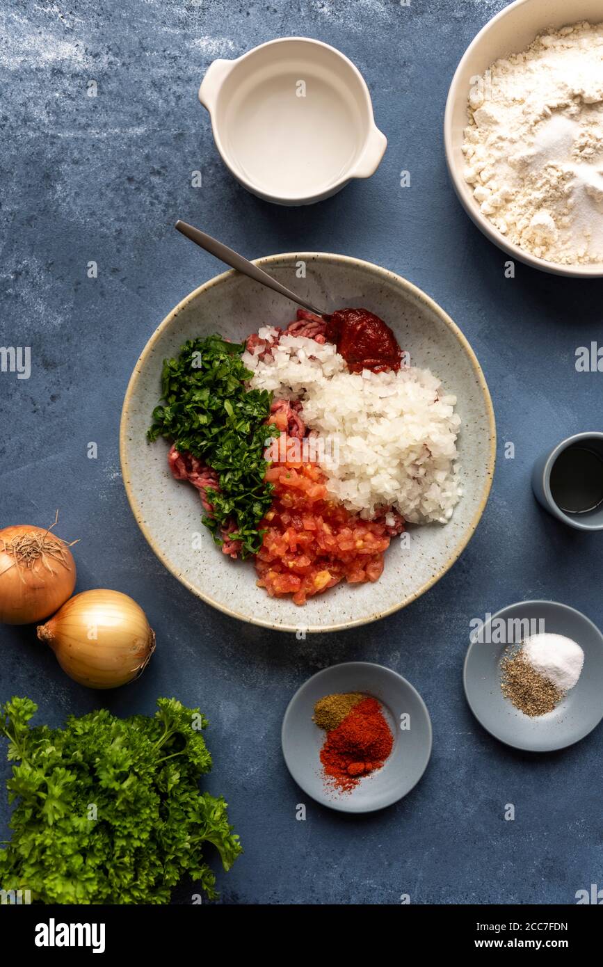 Turkish lahmacun ingredients like ground beef, chopped onions, parsley, tomatoes, tomato paste, spices, cumin. chili powder, black pepper, salt, vineg Stock Photo