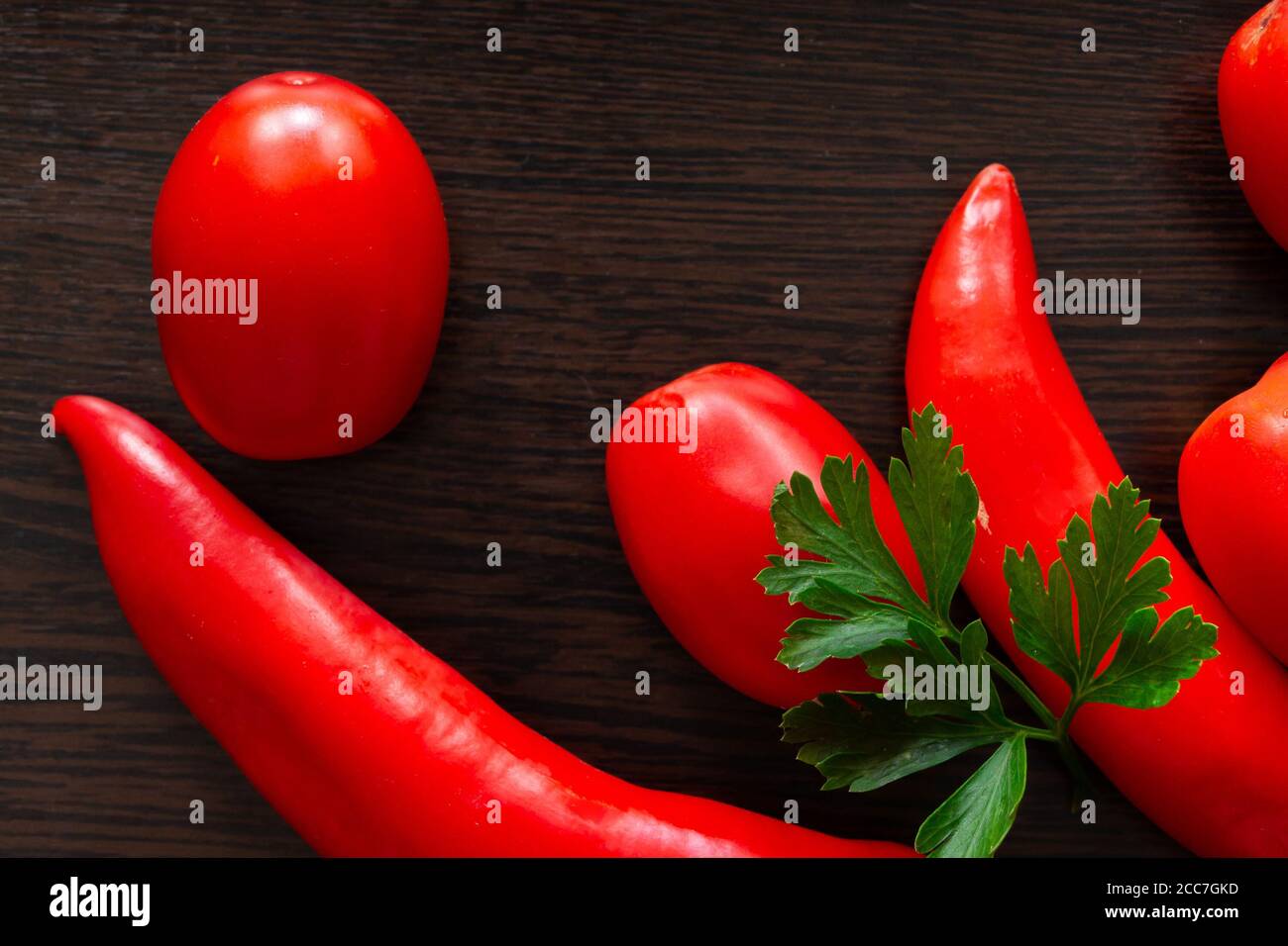 Chili peppers and tomatoes on a dark wooden background Stock Photo - Alamy