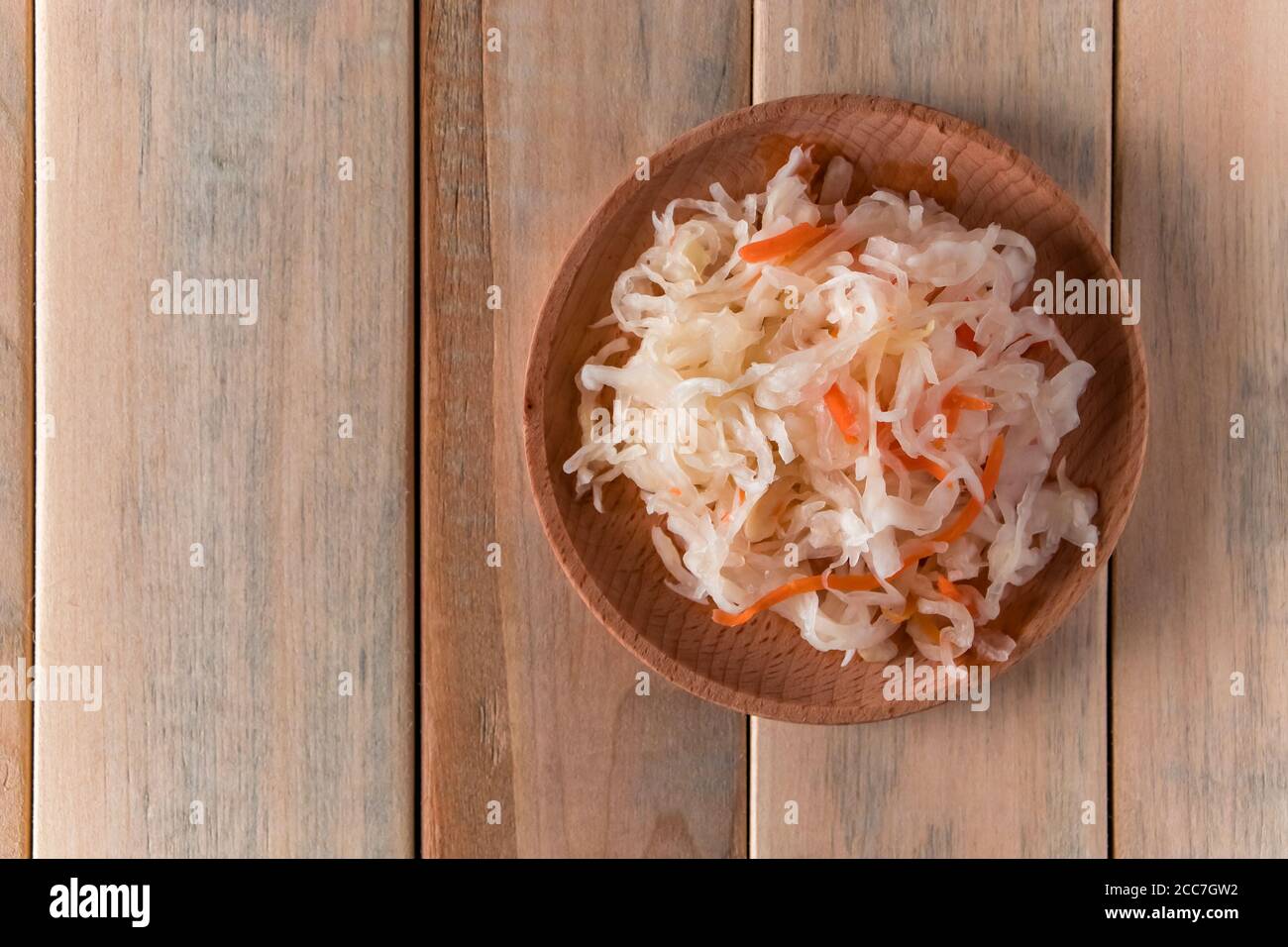 Homemade sauerkraut on a wooden plate. Fermented cabbage with carrot on a light background. Eco food, the trend of healthy eating. Place for your text Stock Photo